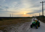Tractor on dirt road at sunset